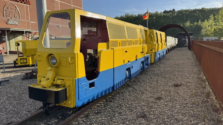 Alte Grubenlok mit ihren Loren – früher unter Tage im Einsatz, heute Teil des Industriedenkmals.